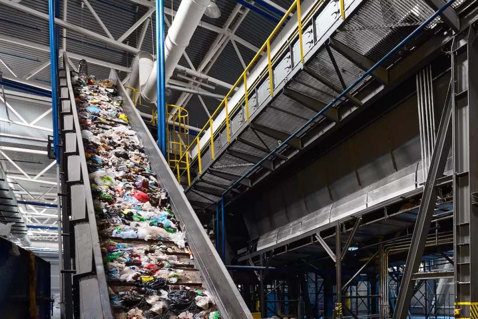 Conveyor belt in industrial recycling center with plastic materials.